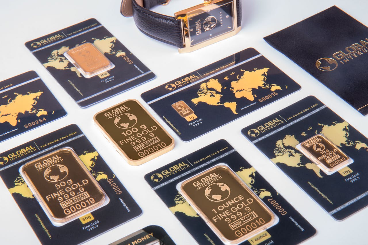 High-angle shot of fine gold bars with a luxury watch and branded packaging.